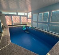 Interior of a family house with a pool and tiles, surrounded by windows letting in light.