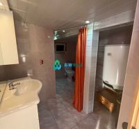 A bathroom in a family house with a sink, a heater, and an orange curtain.