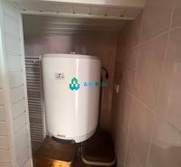A boiler in the bathroom of a family house, next to the radiator and the basket, with a ceramic floor.