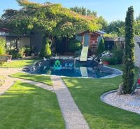 A family house in Orechová Potôň with a garden, lawn, swimming pool, and flowers.
