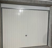 A closed metal garage door in a 3-room apartment with concrete walls.