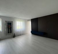 The interior of a spacious room with a white floor and dark walls in a 3-room apartment.