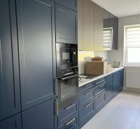 A kitchen in a 3-room apartment with dark blue cabinets and a wooden decor floor.