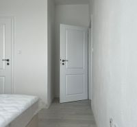 A bedroom with white walls and a wooden decor floor in a three-room apartment.
