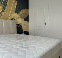 A bedroom in a 3-room apartment with an upholstered bed and golden wallpaper.