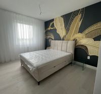 A bedroom in a 3-room apartment with decorative wallpaper and a wooden decor floor.