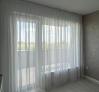 White curtain in a 3-room apartment, floor with wooden decor and light wall.