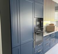 A kitchen in a 3-room apartment with dark blue built-in cabinets and appliances.