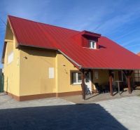 Yellow building with a red roof in Dunajská Streda, paved courtyard and sidewalk.