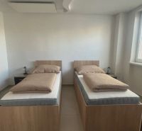 A room with two single beds and nightstands in a building.