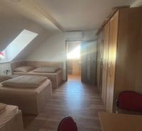 Attic room with single beds, wooden decor flooring, and a built-in wardrobe.