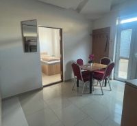 A dining room with a marble floor, a table with chairs, and an entrance to a bedroom in a building.