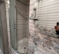 Bathroom with floral tiles and a shower in a studio apartment.