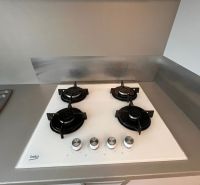 A gas stove with four burners and stainless steel control knobs in a studio apartment.