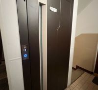 There is a brown elevator with a digital panel in the apartment building.