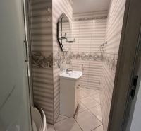 Bathroom with a bathtub, sink, and mirror in a studio apartment.