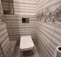 A toilet in a one-room apartment with decorative tiles and a floral motif.