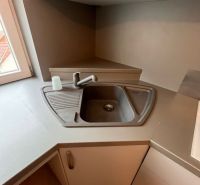 Kitchen area with a corner sink and faucet in a studio apartment.