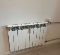 Radiator on the wall with a wooden decor floor in a studio apartment.