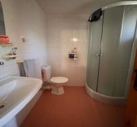 A bathroom in a family house with a bathtub, shower, and white tiles.