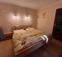 A bedroom in a family house with a large bed and a floor with a wooden decor.