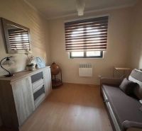 A room in a family house with a wooden decor floor and a darkened window.