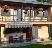 A family house in Gabčíkovo with a balcony, an awning, and flowers on the windows.