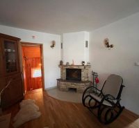A room in a family house with a fireplace, a rocking chair, and a floor with a wooden decor.