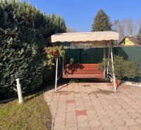 The garden of a family house in Gabčíkovo with a swing, built into a tiled terrace.