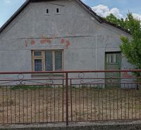 A family house in Ňárad with an old facade, a fence, and closed windows.