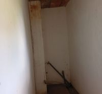 A narrow space in a family house with thick white walls and a wooden ceiling.