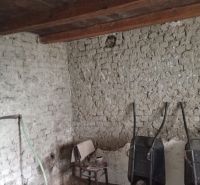 Interior of a family house with brick walls, a chair, and two wheelbarrows.