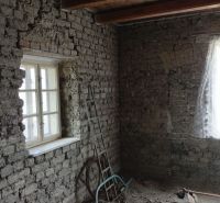 Stone wall, light blue ladder, and a window with a white curtain in a family house.