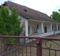 A family house in Ňárad with a white facade and a sloped roof with a wooden fence.