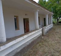 A family house in Ňárad with white columns and a veranda, surrounded by greenery.