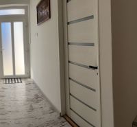 A hallway of a family house with a wooden decor floor and light-colored doors.