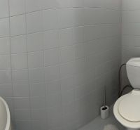 Bathroom with white tiles, a sink, and a toilet in a family house.