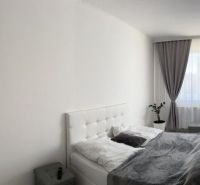 A bedroom in a family house with white furniture, gray curtains, and a decorative mirror.