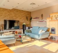 Living room in a family house with upholstered furniture, a television, and tiled stoves.
