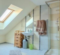 A bathroom with skylight lighting, featuring a shower and a sink in a family house.