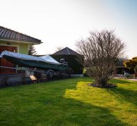 A garden at a family house in Dolný Bar with a boat on a trailer and a well-maintained lawn.