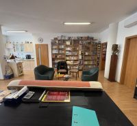 Living room with a library, kitchen, and wooden decor flooring in a 3-room apartment.