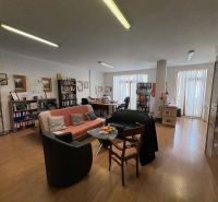 Living room with a sofa, bookshelf, desk, and wooden decor flooring.