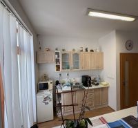 A kitchen in a 3-room apartment with a wooden decor floor and kitchen cabinets.