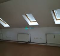 An attic office with radiators, windows, and a wooden decor floor.