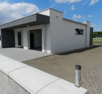 A family house in Dolný Bar with a fence and a paved area under the blue sky.