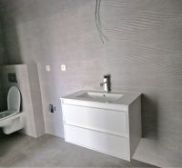 A bathroom in a 3-room apartment with a white sink and gray tiles.