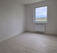 A room with white walls and a wooden decor floor in a 3-room apartment.