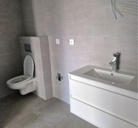 Bathroom in a 3-room apartment with a toilet and a sink, tiles with a neutral design.