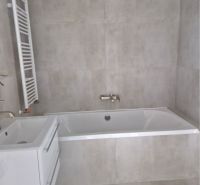 Bathroom in a 3-room apartment with a bathtub and a sink, light tiles on the walls.